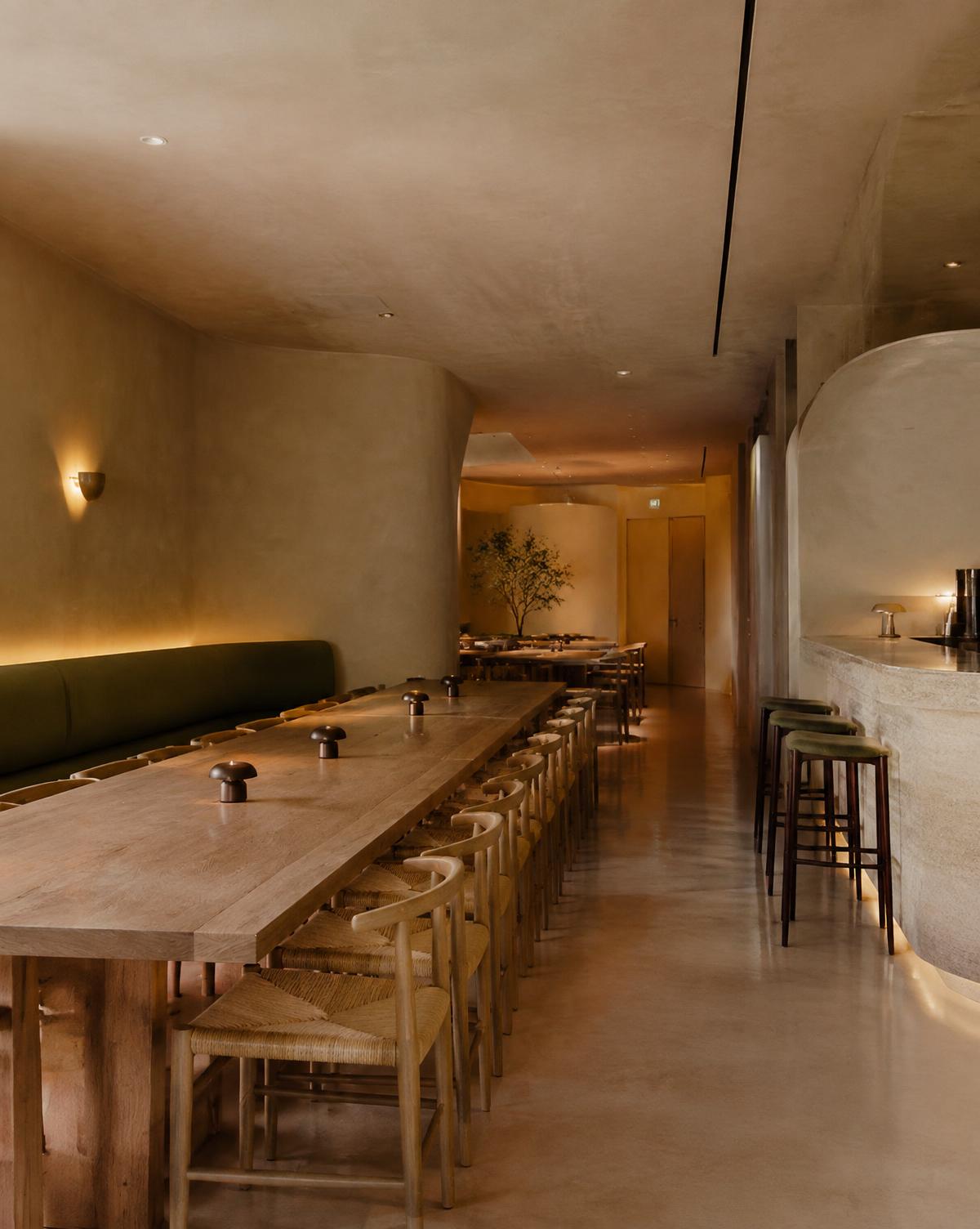 Restaurant interior with curved plaster walls and a long oak table